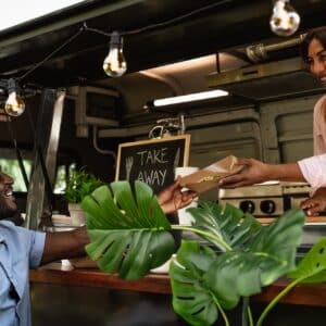 Young African man buying meal from food truck - Modern business and take away concept