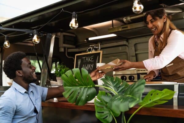 Young African man buying meal from food truck - Modern business and take away concept
